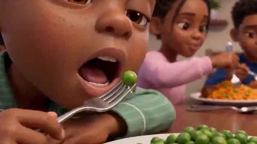 Mahdi looking sleepy while holding a forkful of peas at the dinner table.