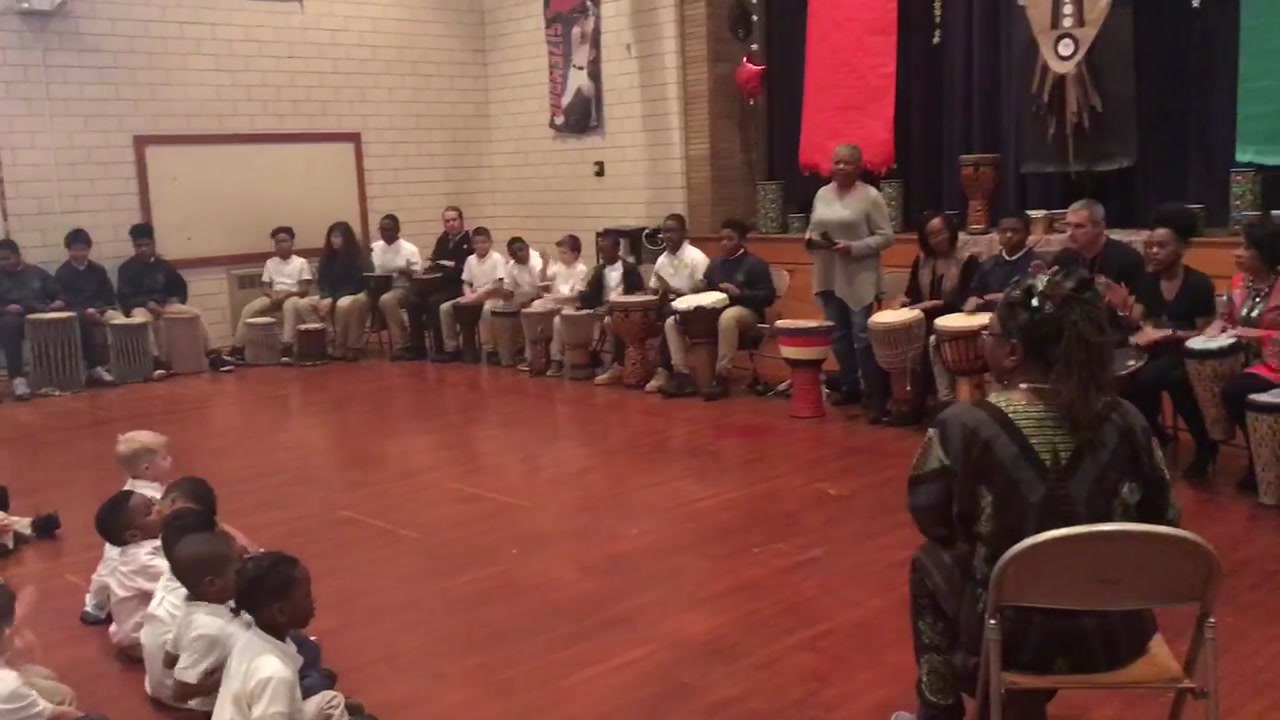 Mama Fasi leading an engaging drumming lesson for diverse elementary school students